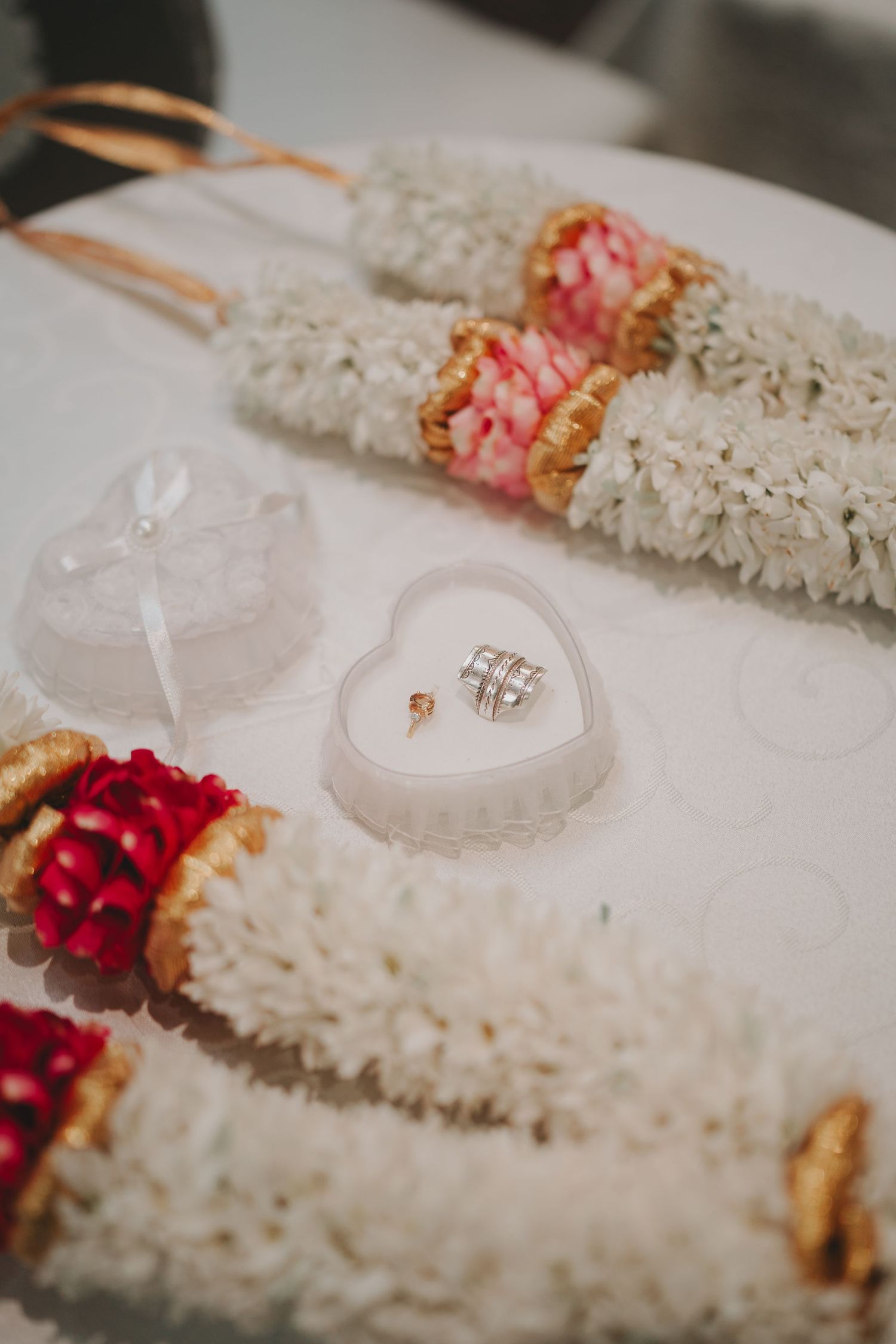Wedding rings displayed in heart-shaped case with floral garlands.