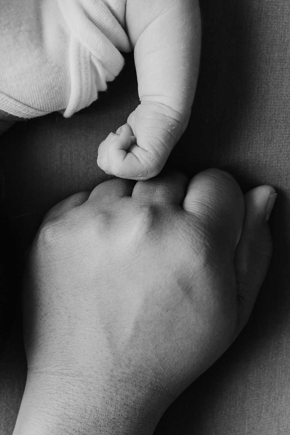 Black and white image comparing adult and baby hands side by side.