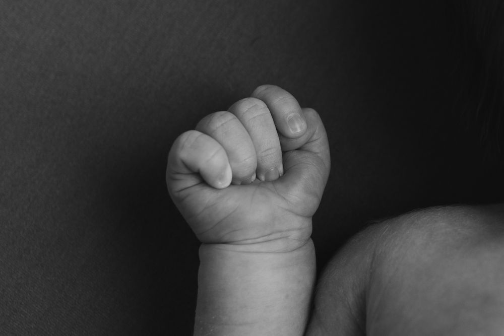 Black and white close-up of baby's tiny clenched fist.