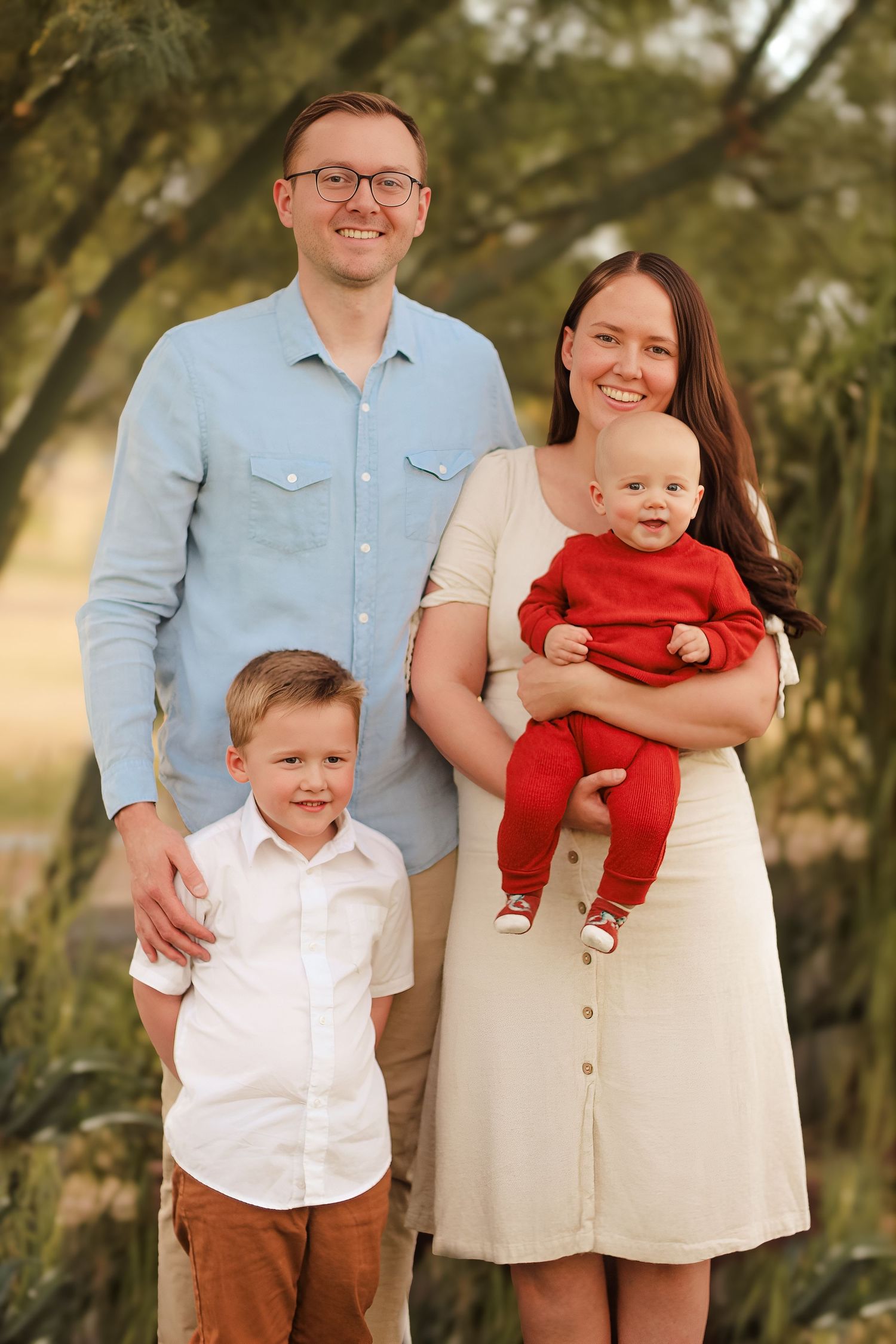 Family of four poses together outdoors in coordinated casual outfits.