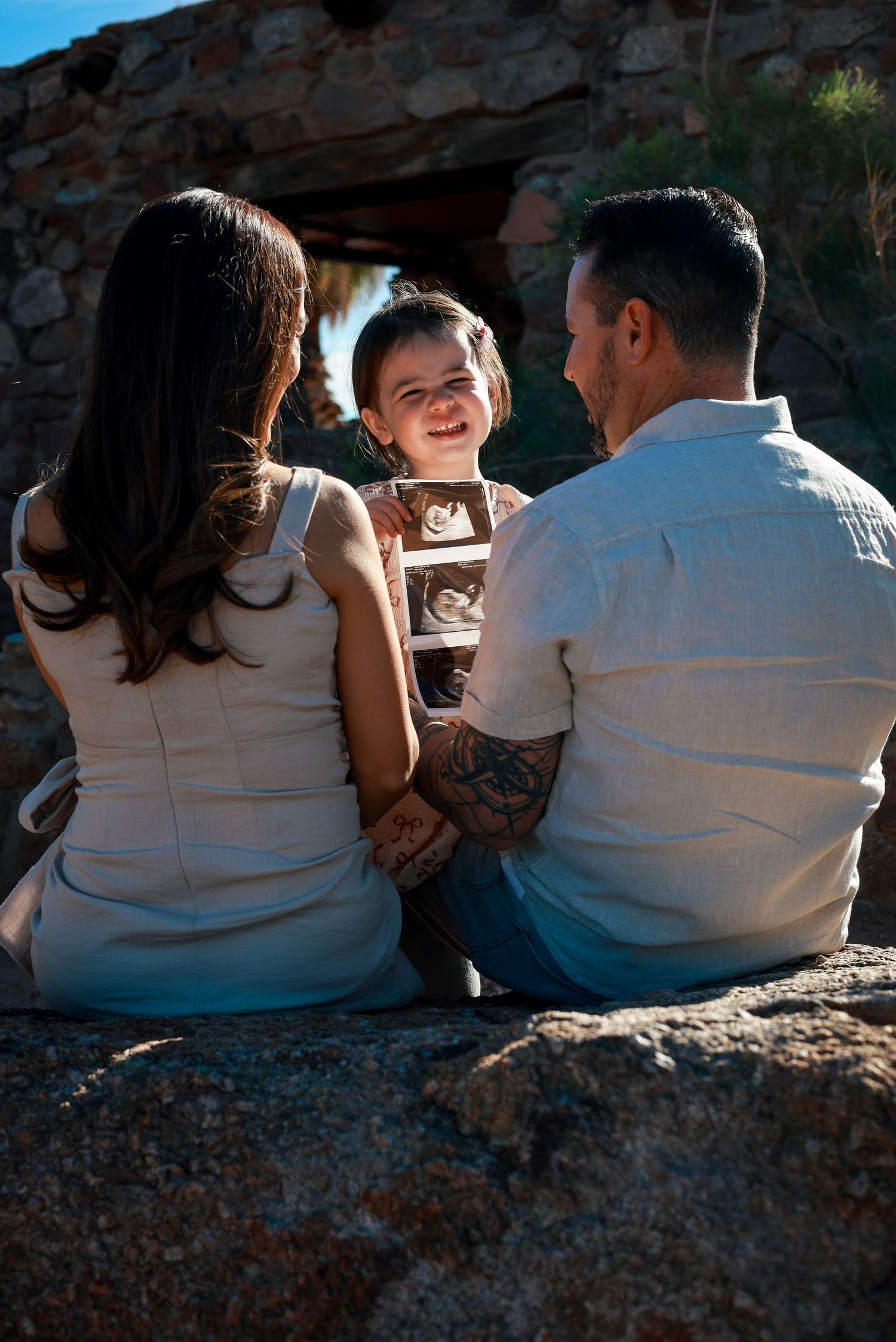 A couple sits together on a stone wall at sunset, shown in a series of intimate candid shots.
