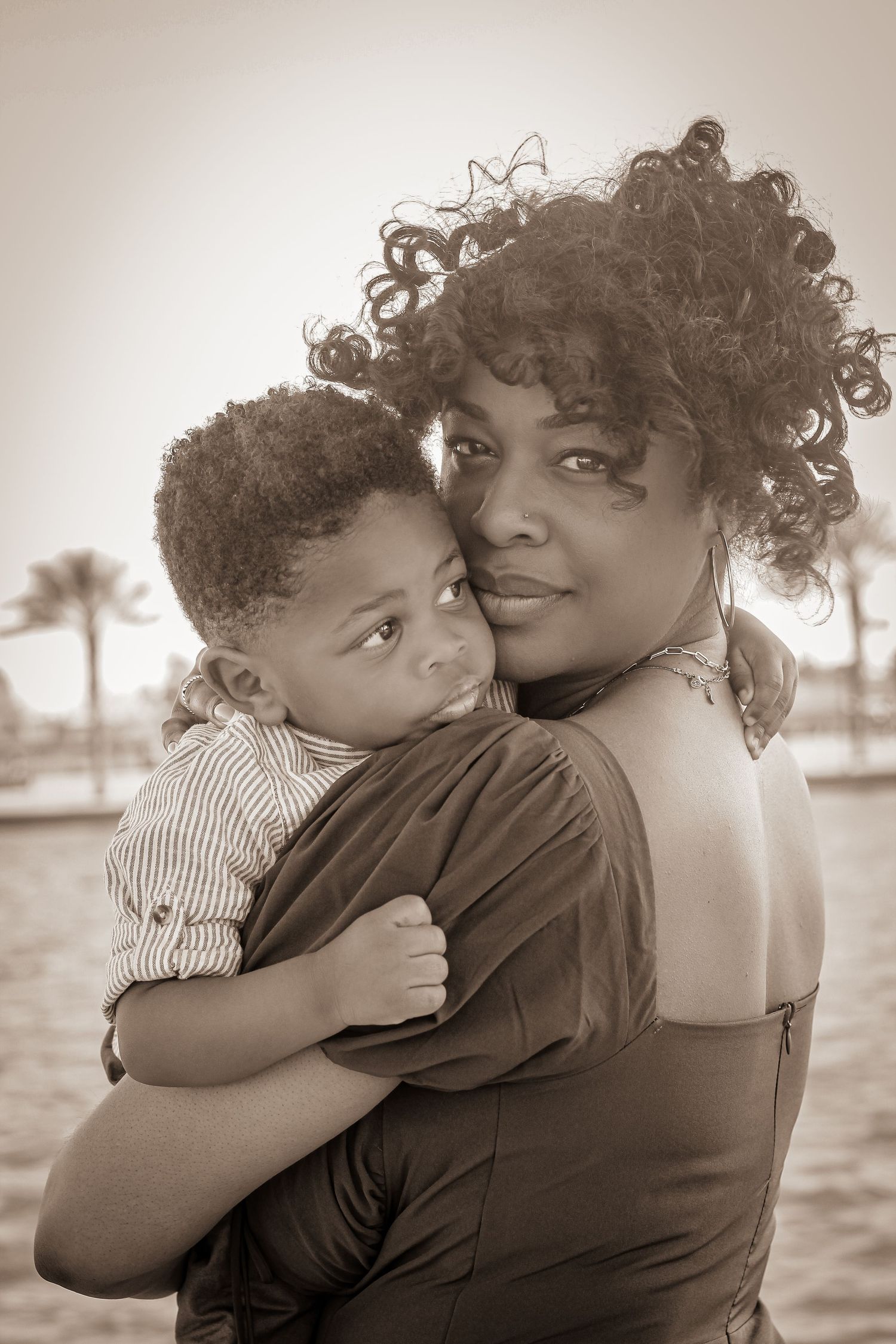 Intimate black and white portrait of parent and child embracing outdoors.