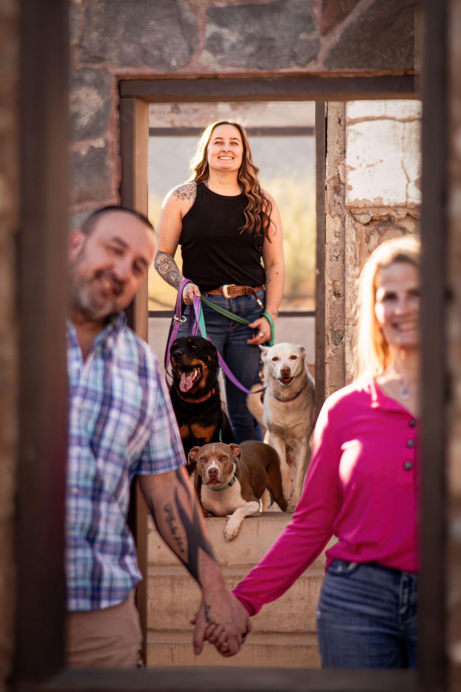 Family portrait through stone doorframe with two dogs and warm sunset lighting.