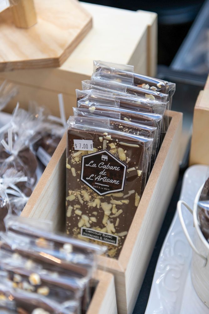 La Cabane de L'Artisan chocolate bars displayed in a wooden box at a artisan chocolate shop.