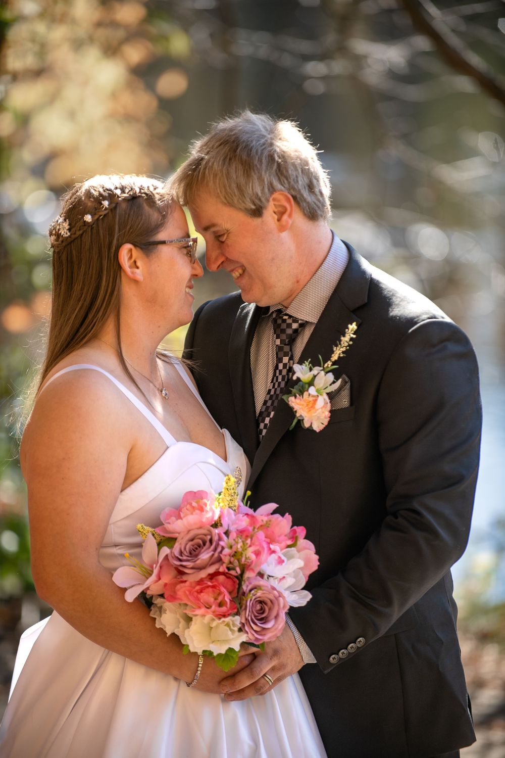 A romantic wedding couple shares intimate moments in a garden setting with pink and coral floral bouquet details.