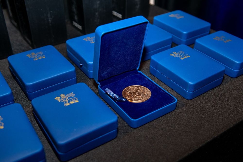 Blue velvet presentation boxes with gold medals on a table at an awards ceremony.