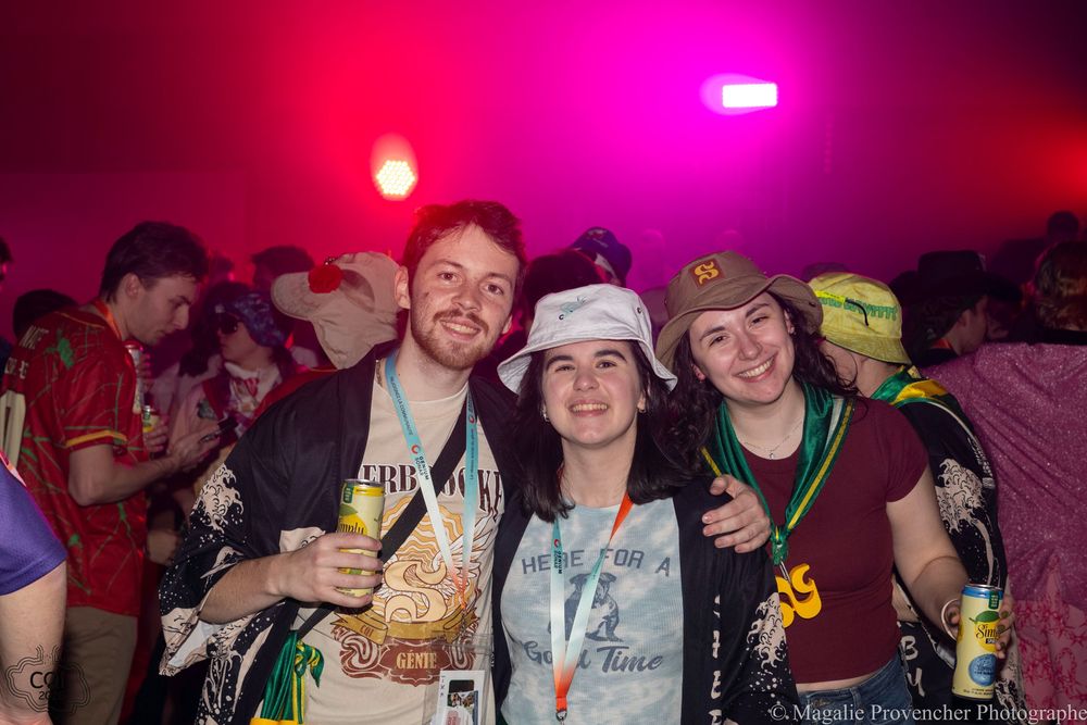 Group of people enjoying a nightclub or party atmosphere with bright red and pink lighting in the background.