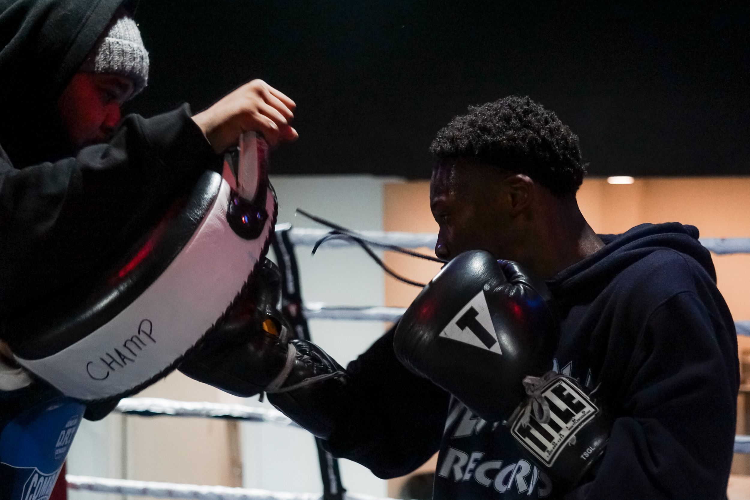 Athlete training with focus mitts and boxing equipment during an indoor workout session at a gym facility.