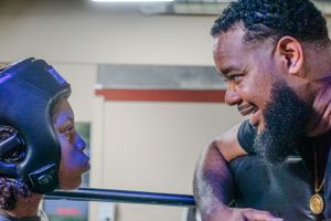 A boxing coach and student share a moment during training at the gym.