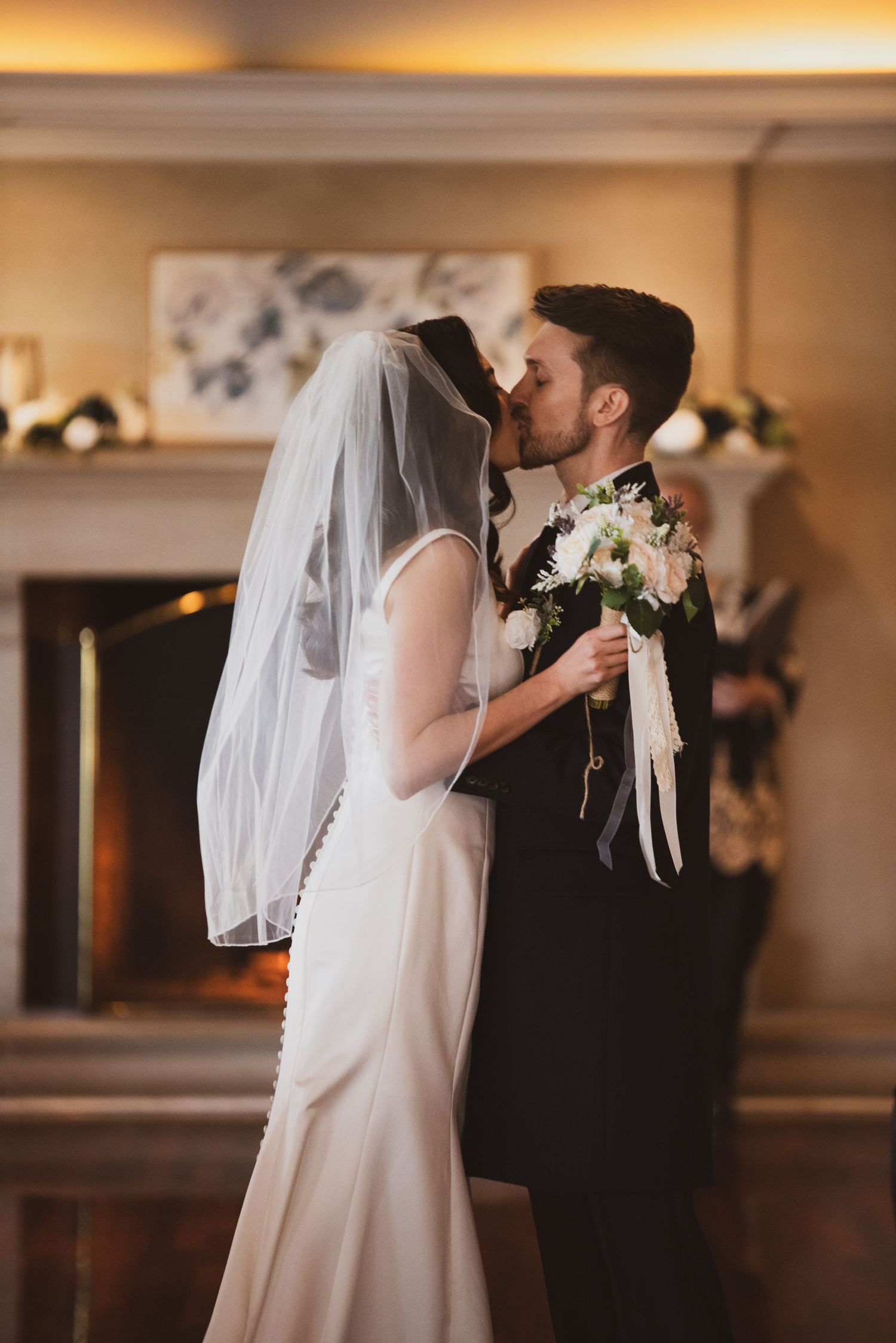 A couple shares their first kiss as newlyweds during their intimate indoor wedding ceremony.