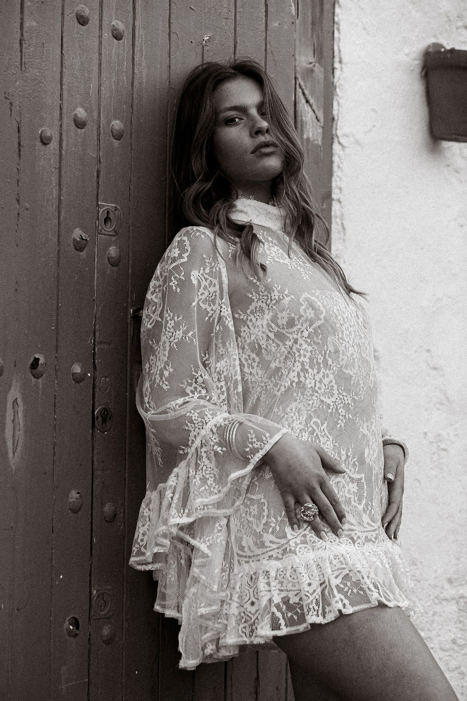 Monochrome fashion shot with vintage lace blouse against rustic door.