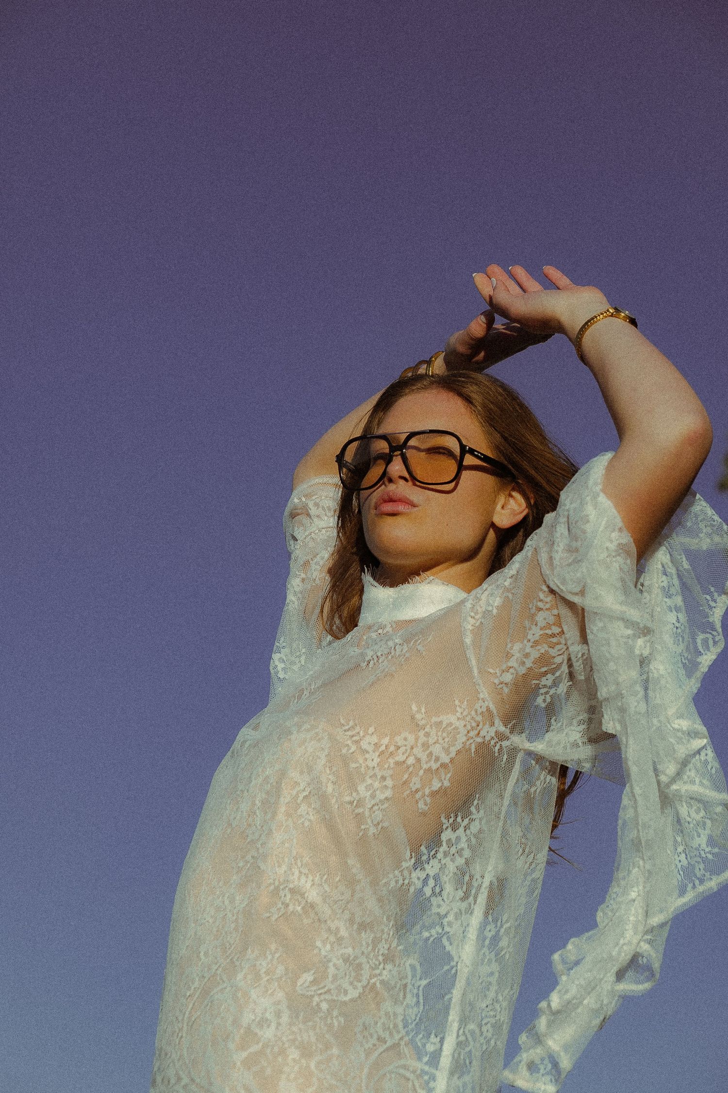 Ethereal fashion portrait featuring delicate white lace top against purple backdrop.