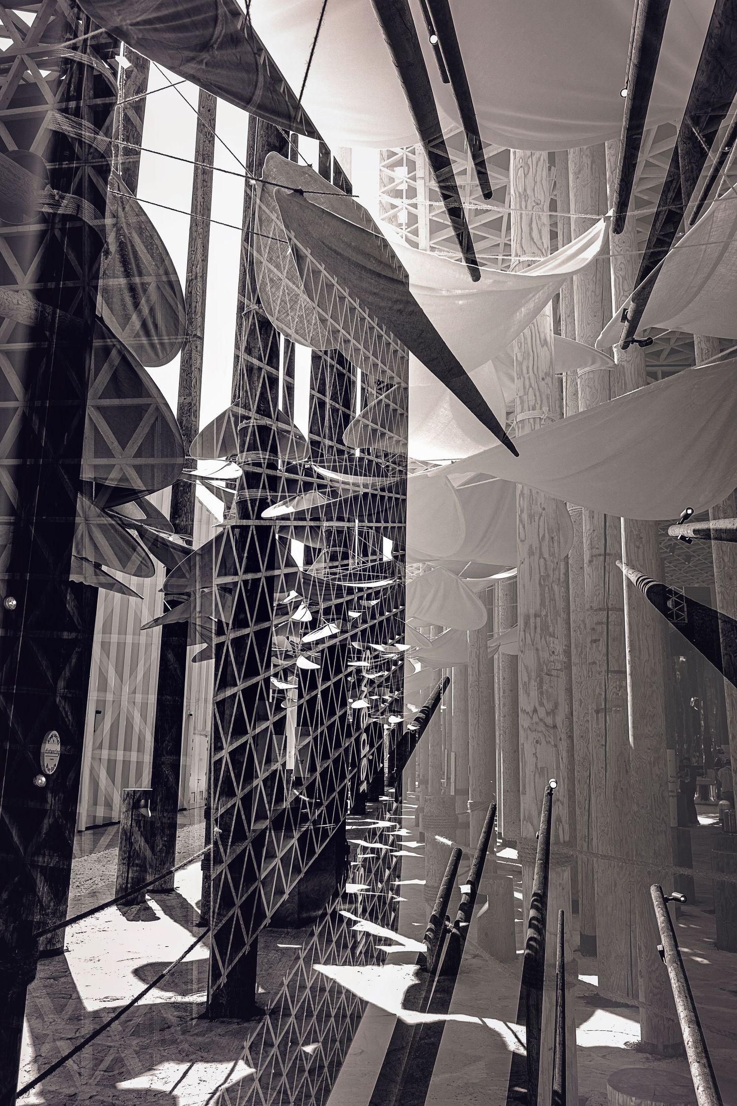 Abstract architectural detail showing geometric patterns and shadows through glass and metal structures in black and white.