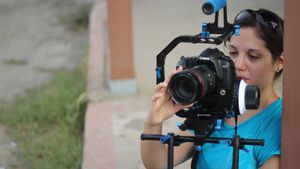 Camera operator using a professional DSLR mounted on a stabilizer rig outdoors.