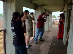 A group of photographers standing in a covered walkway taking pictures through openings.