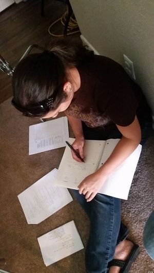 Student bent over paperwork while writing and studying on the floor.