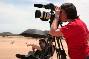 Photographers with professional camera equipment filming in a desert landscape.