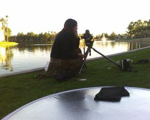 Photographer setting up equipment by a lake during golden hour.