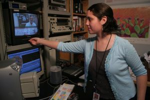 Video editor working at a control panel with multiple monitors.