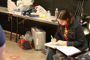 A videographer writing notes while sitting at a table with equipment.
