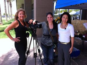 Three filmmakers pose with camera equipment outdoors on a sunny day.
