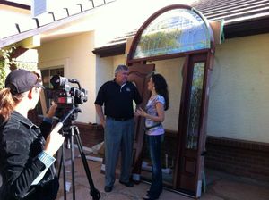 Camera crew recording an interview outside a building with an arched doorway.