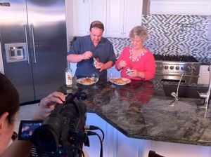 Filming a cooking demonstration with sunflowers in the background on a granite countertop.