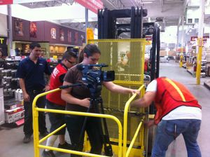 Workers in safety vests gather around machinery in an industrial warehouse setting.
