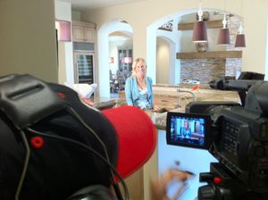 Professional video camera recording setup in a modern kitchen interior.