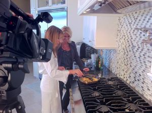 Video production crew filming a cooking demonstration in a modern kitchen.