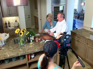 Video production crew filming in a kitchen with sunflowers on the counter.