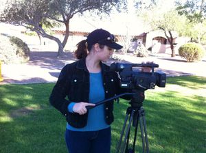 Camera operator filming outdoors with professional equipment on a sunny day.