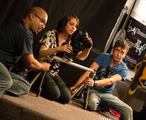 Group of photographers examine camera equipment during a photography workshop.