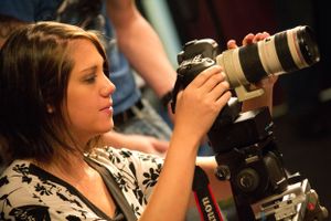 Photographer using professional camera with telephoto lens in studio lighting.