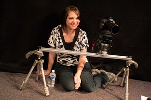 Photographer setting up camera equipment on sliding dolly track.