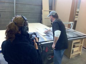 Production crew filming with professional camera equipment in workshop setting.