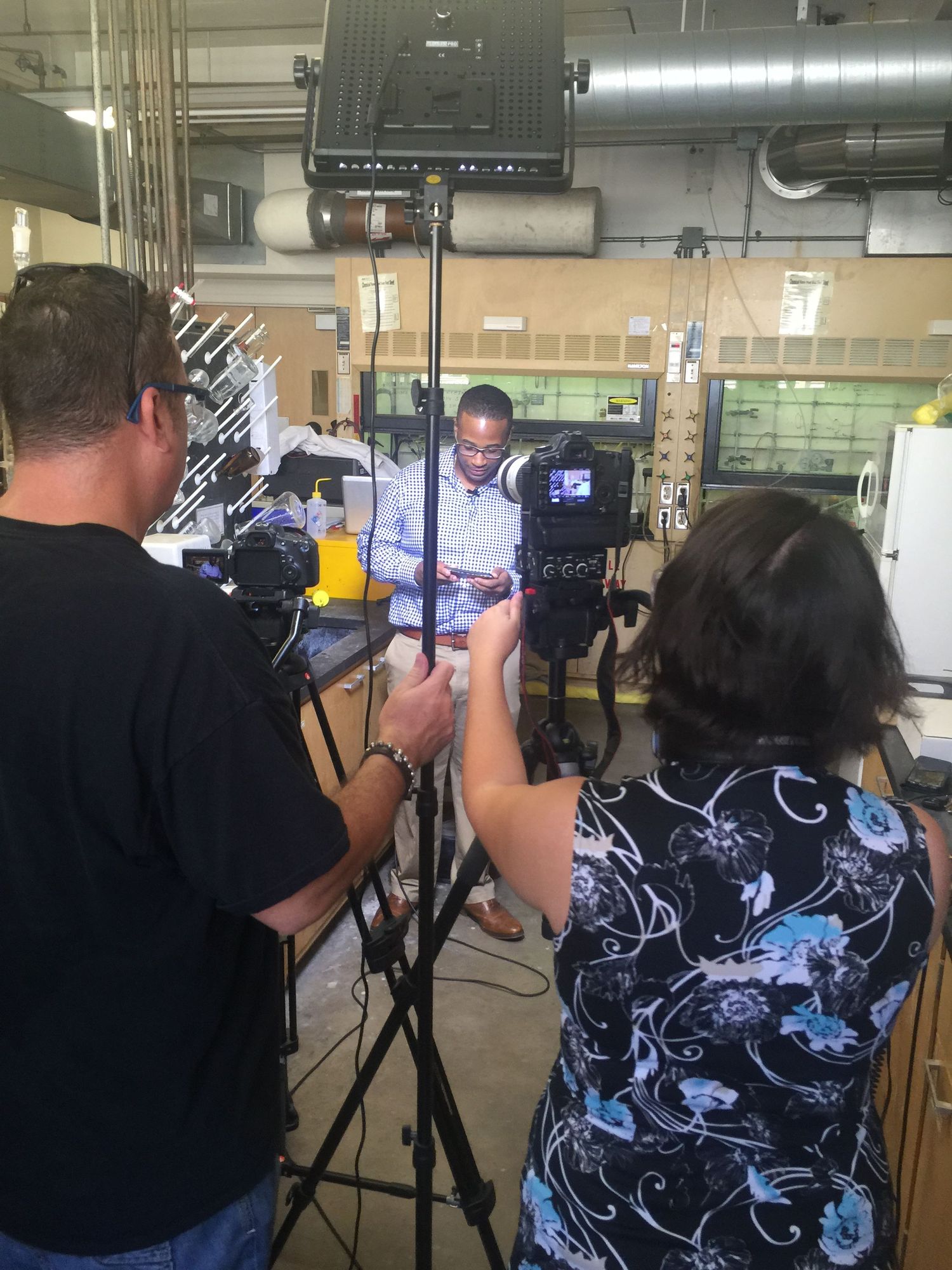 Behind-the-scenes video production shoot in an industrial space with camera crew and lighting equipment.