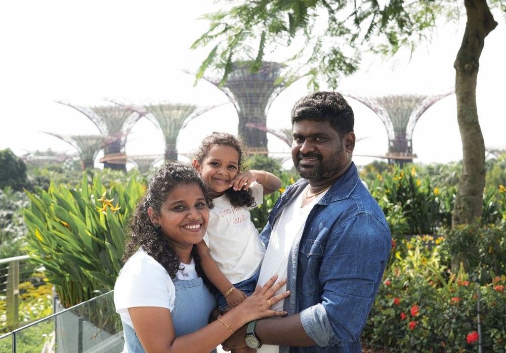 A family poses together at Gardens by the Bay with the Supertree Grove visible in the background.