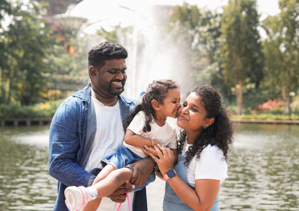 A family shares an affectionate moment together near a water feature.