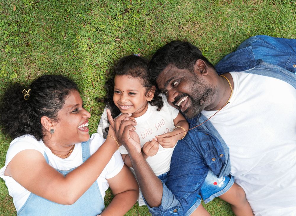 A family lies on grass enjoying playful moments together on a summer day.