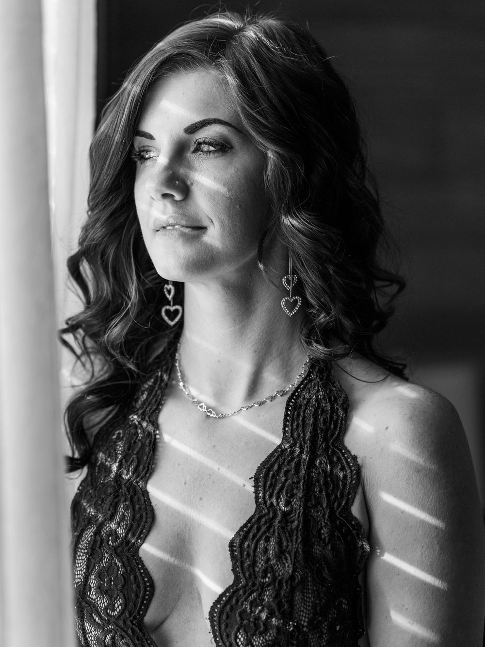 Boudoir portrait of a woman in a black bodysuit in front of a window taken by East Tennessee boudoir photographer in dandridge.