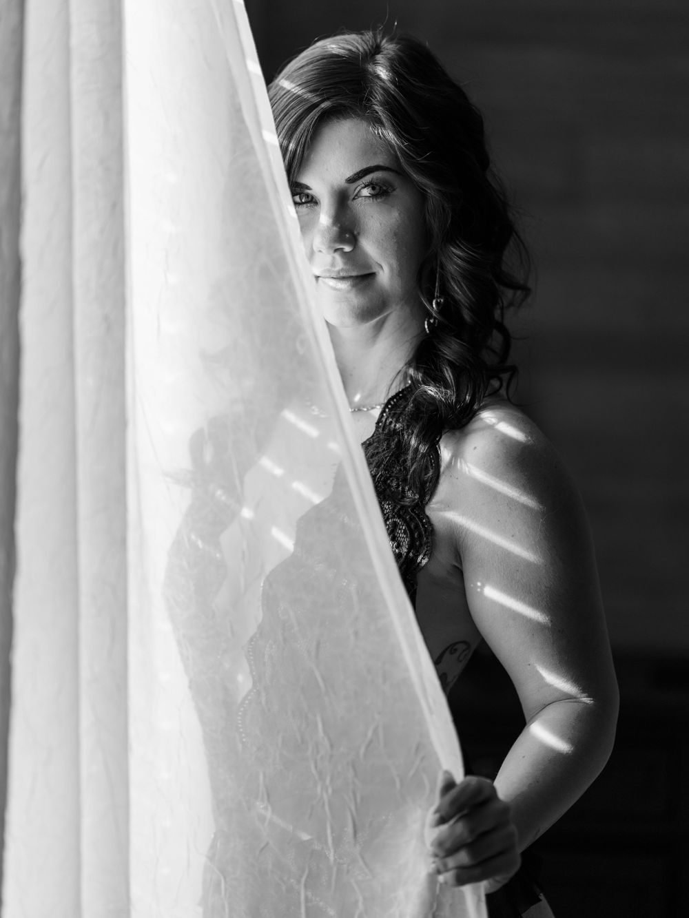 Boudoir portrait of a woman in a black bodysuit in front of a window taken by East Tennessee boudoir photographer in dandridge.