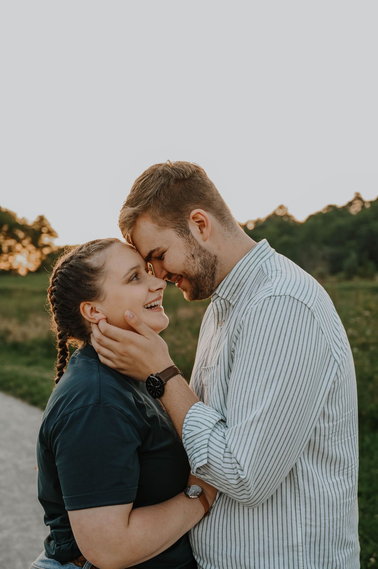 Romantic couple sharing an intimate moment at sunset on a dirt path with trees in the background.
