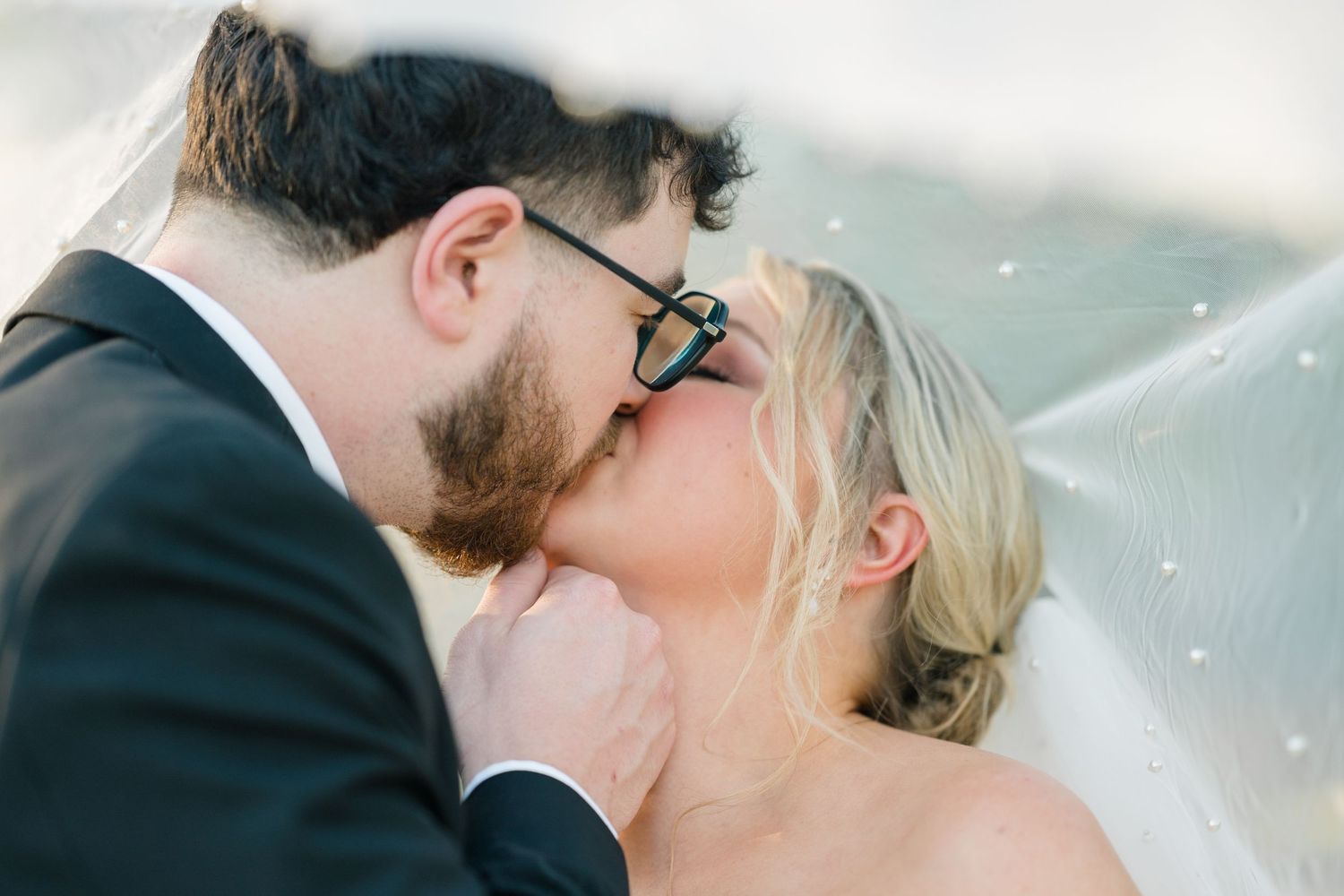 A romantic wedding photo outdoors with a flowing white veil catching the breeze at sunset.