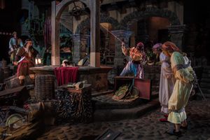 Renaissance period performers enact a dramatic scene inside an ornate stone building with period costumes and props.