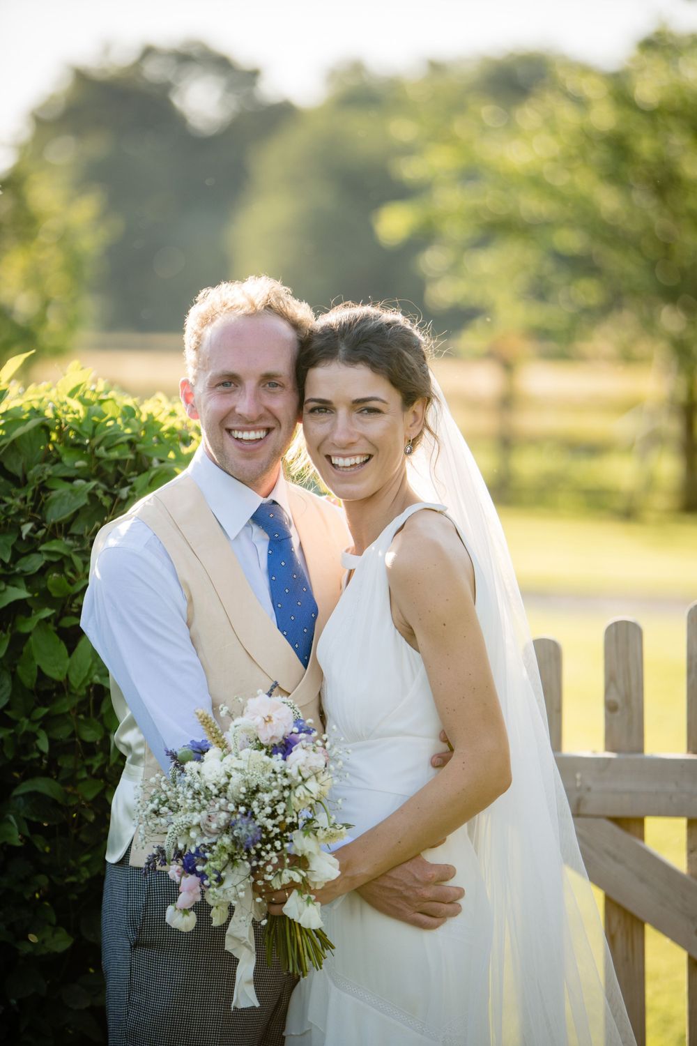 A couple poses together outdoors on their wedding day in Saraguay House, Nova Scotia with the bride holding a delicate bouquet.