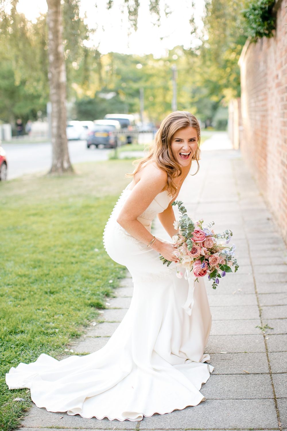 A bride in a flowing white wedding dress smiles while holding a pink and purple bouquet Saraguay House, Nova Scotia.