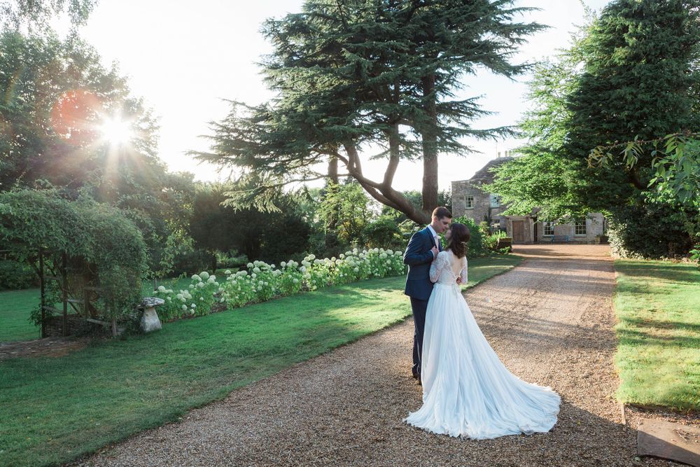 A couple in wedding attire stands in a scenic garden with sunlight peeking through trees Digby Pines Golf Resort and Spa, Wedding photograph
