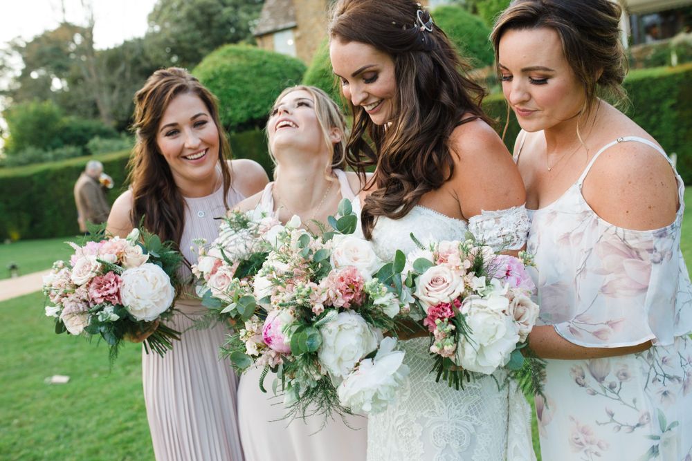 Bridesmaids in soft pastel dresses share a candid laughing moment at Golden Hour for Saraguay House wedding photographer