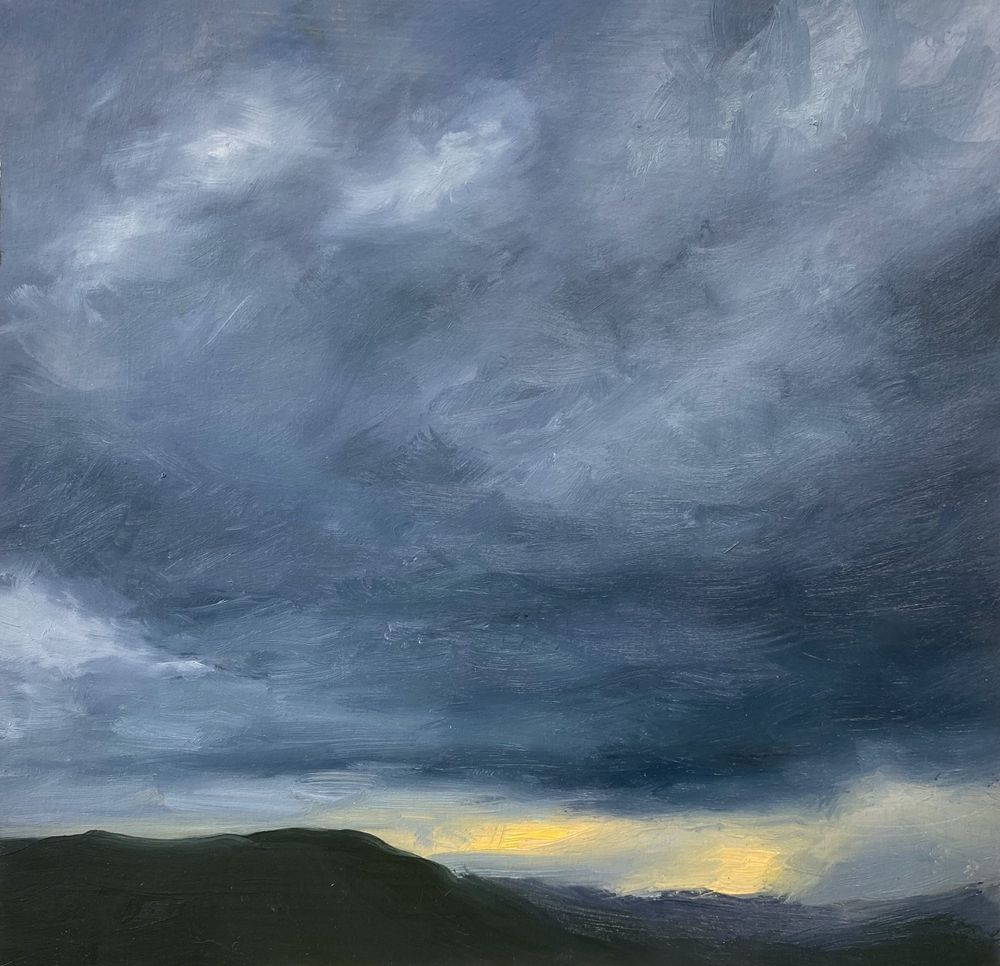 Dark storm clouds over mountains with golden sunlight breaking through on the horizon.